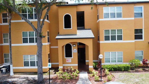 Front view of a multi-story building with orange facade and arched entryway.