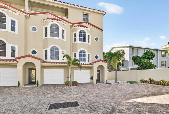 Front view of a multi-story building with arched windows and white garage doors.