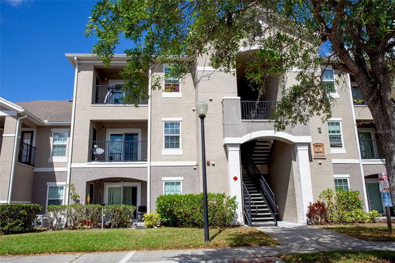 Front view of a multi-story apartment building with balconies and an external staircase.