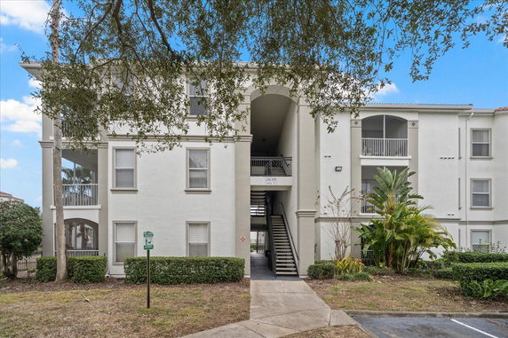 Front view of a multi-story residential building with balconies and central staircase.