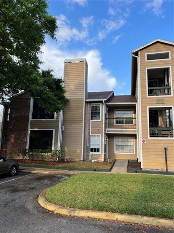 Front view of a multi-story residential building with a chimney and parking area.