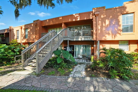 Front view of a two-story building with stairs leading to the upper level and a small patio on the ground level.
