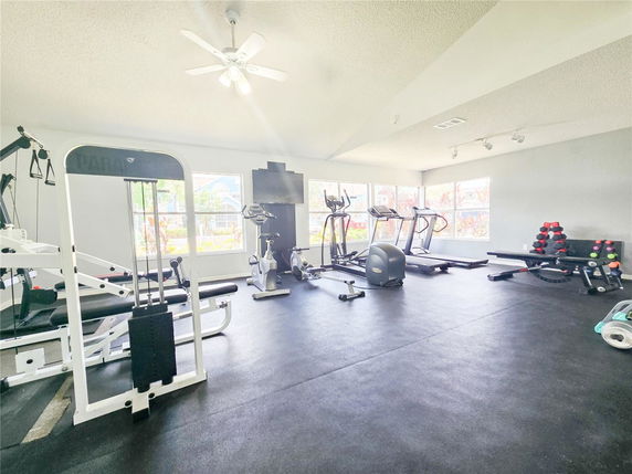 Indoor gym with various exercise equipment and large windows.