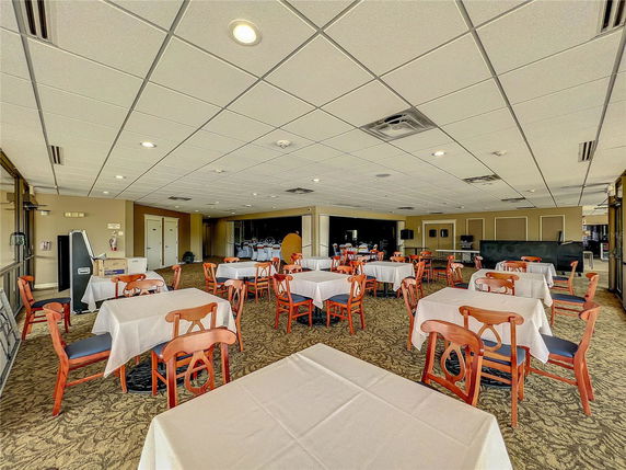 Interior of a club house with tables and chairs arranged in a spacious area.