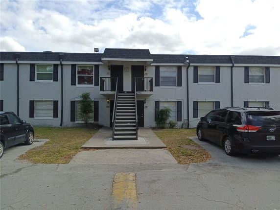 Front view of a two-story apartment building with central staircase and parked cars.