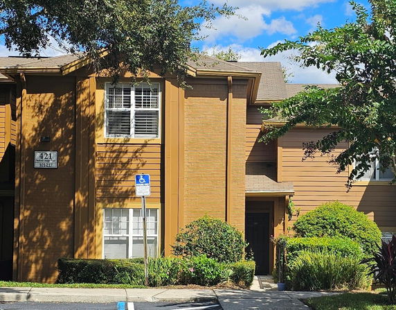 Front view of a brown townhouse with white windows and a visible parking space.