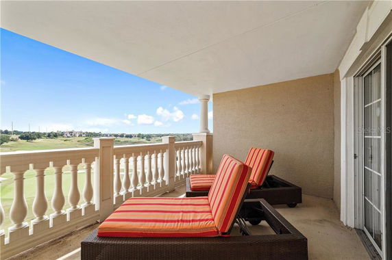 Balcony with lounge chairs and railing overlooking a scenic landscape.