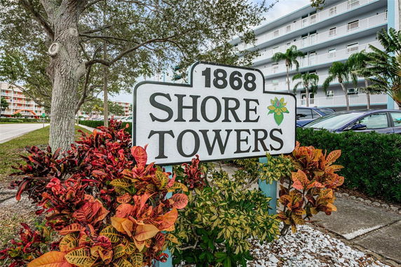 Front view of a multi-story residential building with balconies and a sign labeled '1868 Shore Towers.'