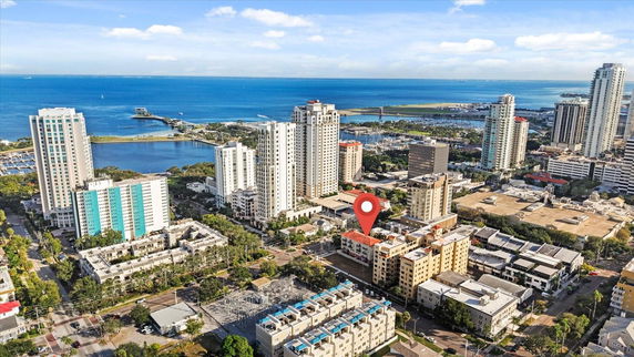 Aerial view of a coastal city with high-rise buildings and a large body of water in the background.