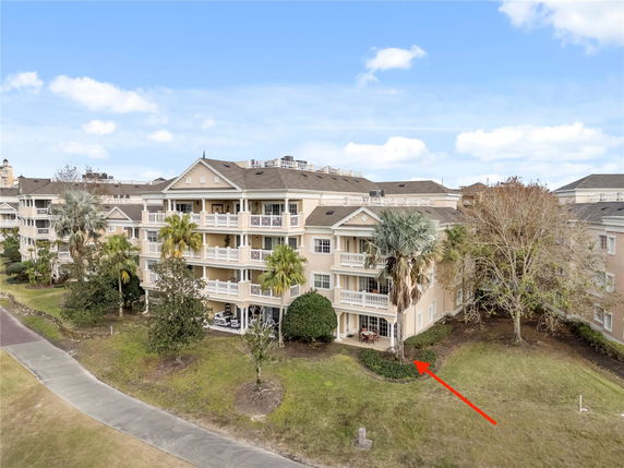 Front view of a multi-story residential building with balconies and palm trees.