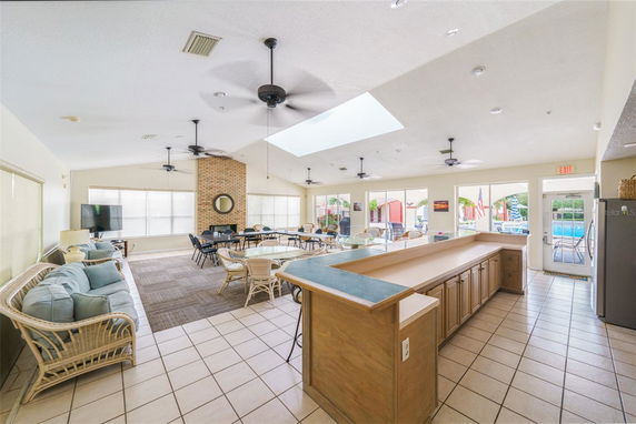 Interior view of a clubhouse with seating and tables, featuring a brick wall and ceiling fans.
