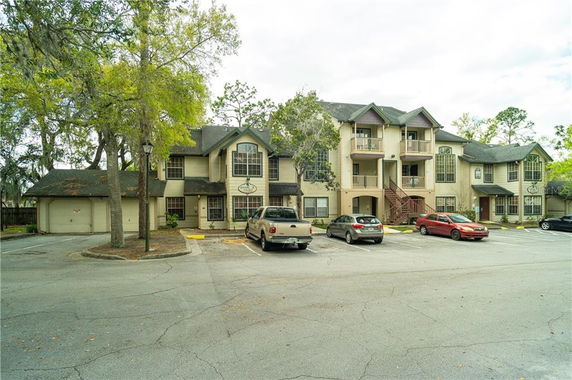 Front view of a residential building with multiple balconies and parked cars in front.