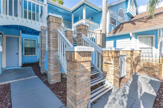 Front view of a two-story house with blue siding and brick columns.