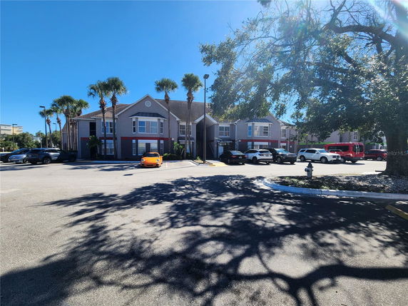 Front view of a two-story building with multiple windows and palm trees in the parking area.