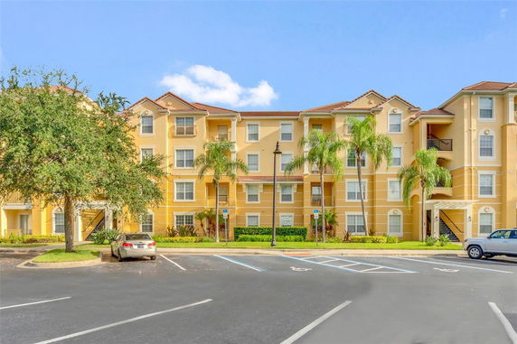 Front view of a multi-story residential building with yellow facade and balconies.
