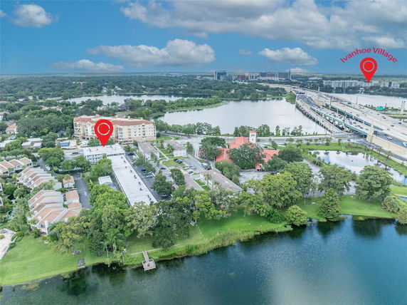 Aerial view of a residential area near a lake with roads and buildings in the background.
