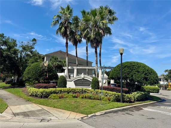 Front view of a condominium building with landscaped gardens and palm trees.