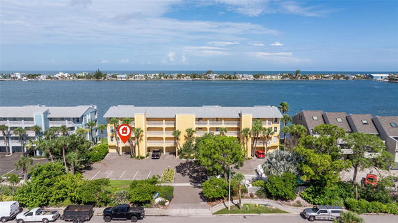 Front view of a yellow condominium building near a body of water.