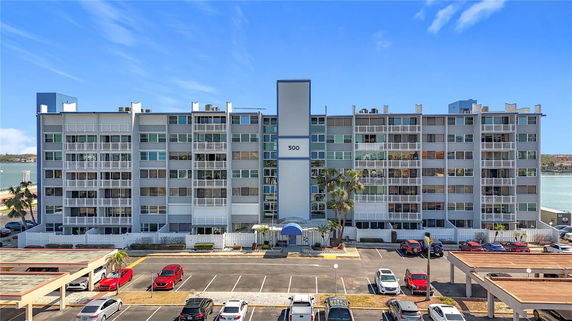 Front view of a multi-story residential building with a parking area in front.