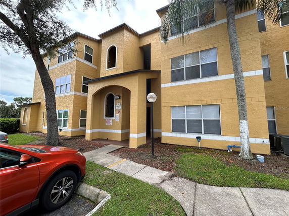 Front view of a multi-story residential building with arched entrance and multiple windows.