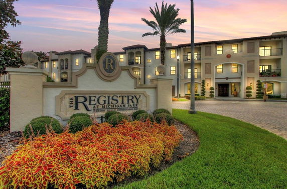 Front view of a resort-style multi-story residential building with landscaped surroundings.