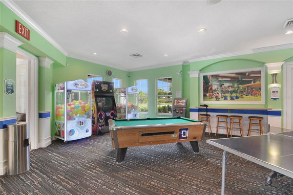 Indoor recreational area with arcade machines, a pool table, and seating.