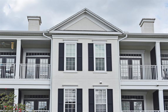 Front view of a multi-story building with balconies and black shutters.