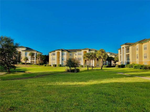Front view of a multi-story apartment building with balconies and a landscaped lawn.