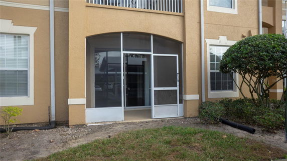 Front view of a building with a screened entry and beige exterior.