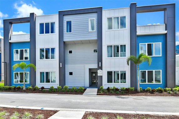 Front view of a modern multi-story building with vibrant blue and white panels.