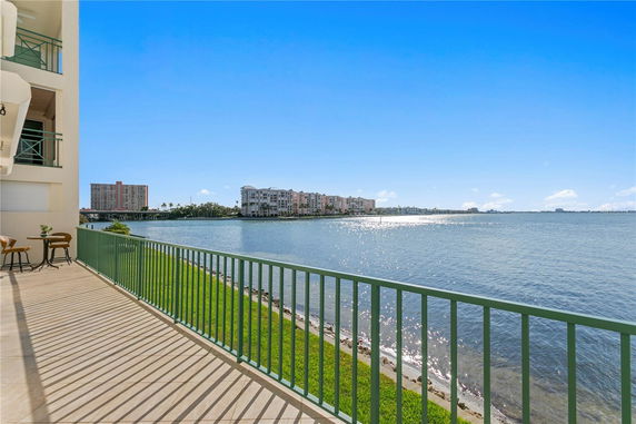 Panoramic view of a waterfront with buildings in the background, seen from a balcony with a railing.