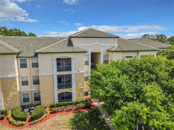 Front view of a multi-story apartment building with balconies and tiled roof.