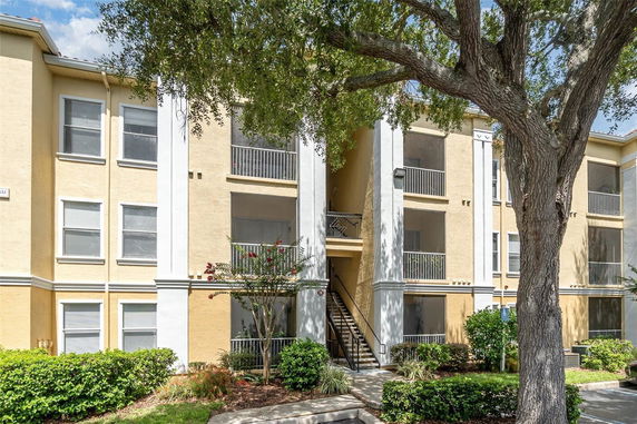 Front view of a three-story apartment building with balconies and a central staircase.