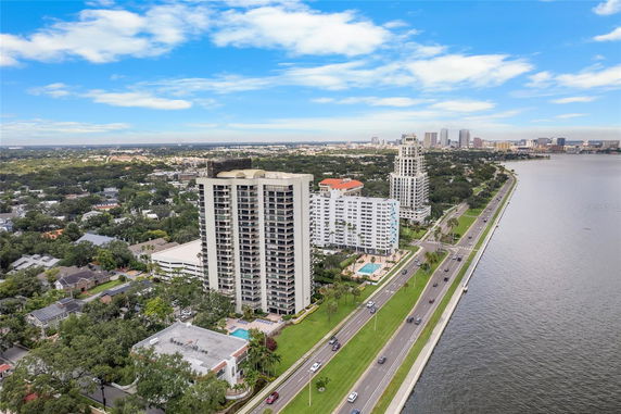 Panoramic view of a waterfront with high-rise buildings and a road along the water.