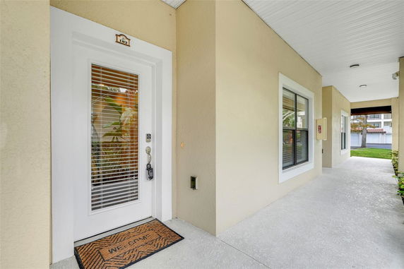 Front view of a building entrance with a white door and a welcome mat.