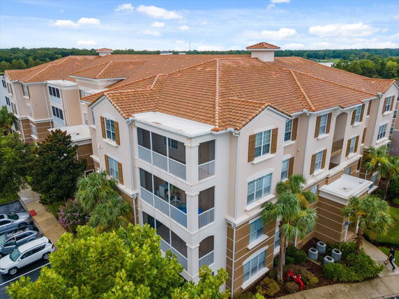 Front view of a multi-story residential building with a red tiled roof and multiple balconies.