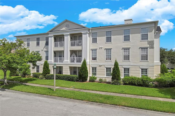 Front view of a large, three-story residential building with multiple balconies and windows.
