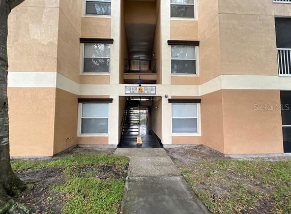Front view of a multi-story apartment building with exterior walkways and multiple windows.
