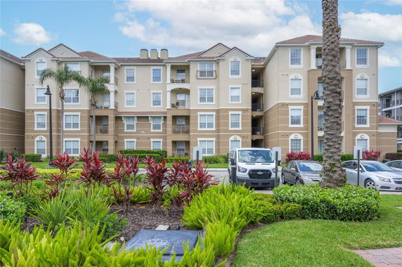 Front view of a multi-story apartment building with balconies and symmetrical windows.