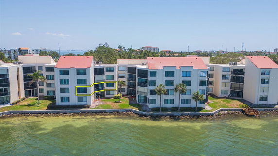 Front view of apartment buildings by the water with multiple floors and red-tiled roofs.