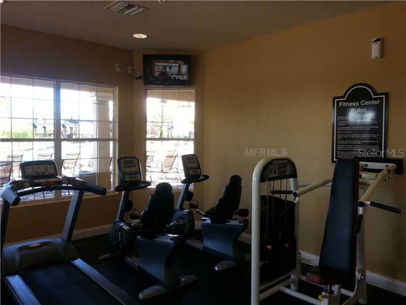 Interior of a fitness center with exercise equipment and a wall-mounted TV.