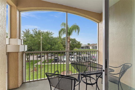 View from a balcony showing surrounding area with trees and parked cars.