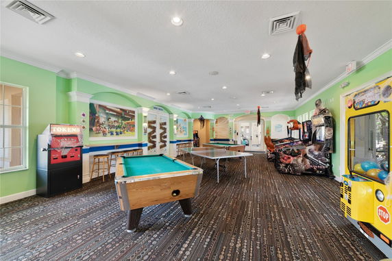 Interior view of a recreational room with pool and ping pong tables, arcade games, and seating areas.