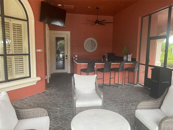 Indoor seating area with a bar counter, chairs, and a mounted TV.