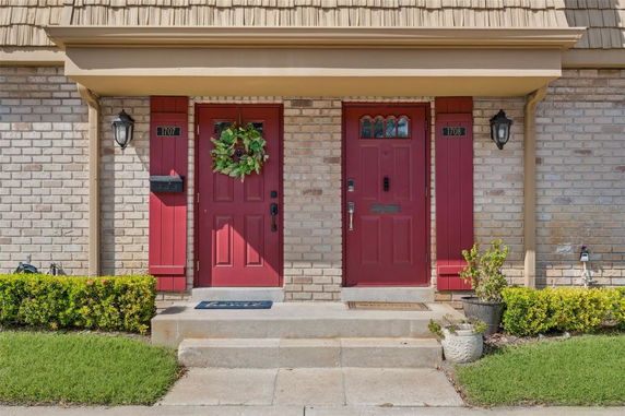 Front view of a building with two red doors and decorative brickwork.