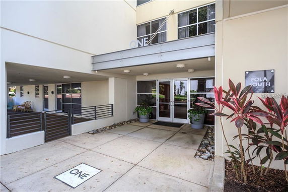 Front view of a building entrance with a covered walkway and glass doors.