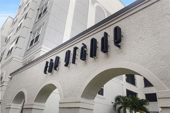 Front view of a building with arches and a sign on the wall.