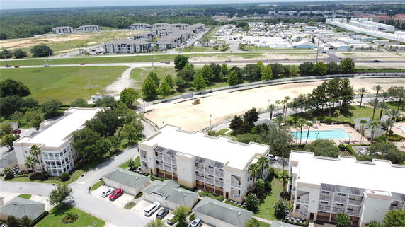 Aerial view of a residential area with multiple apartment buildings, a swimming pool, and surrounding greenery.