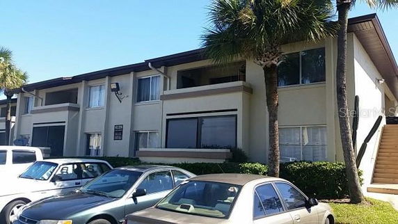 Front view of a two-story apartment building with parked cars in front.