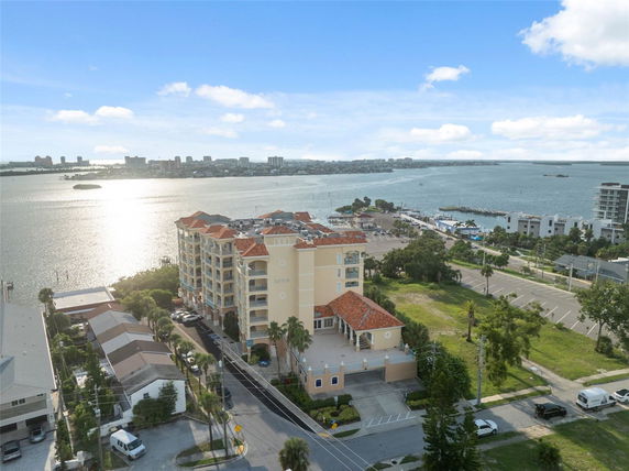 Aerial view of a waterfront building complex with surrounding landscape and water.